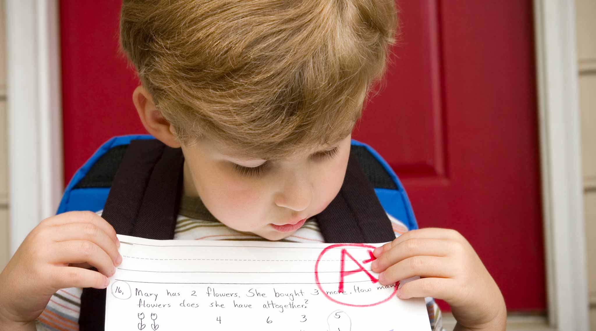 A young child holds a paper with an &quot;A+&quot;