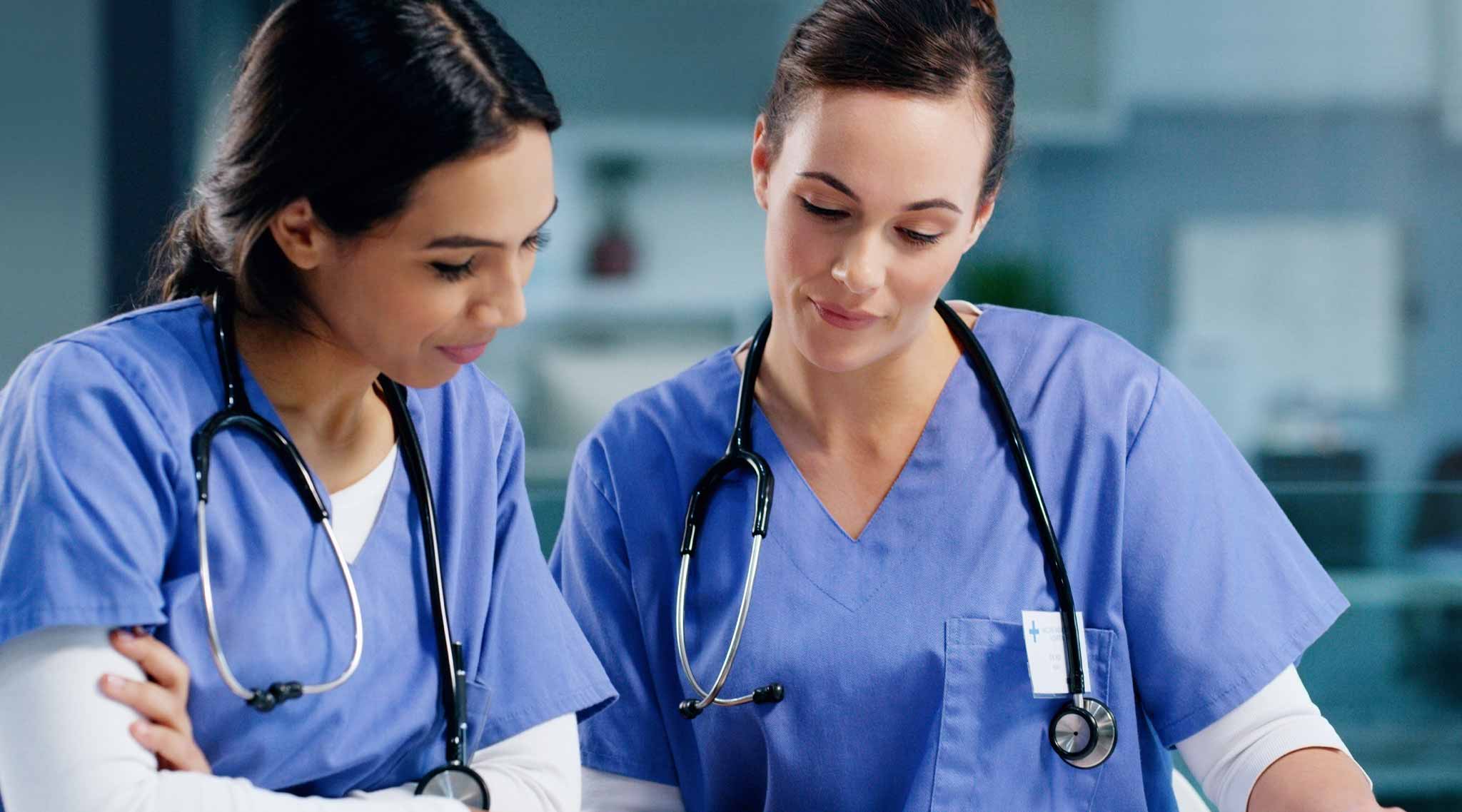 Two nurses looking down at a document.