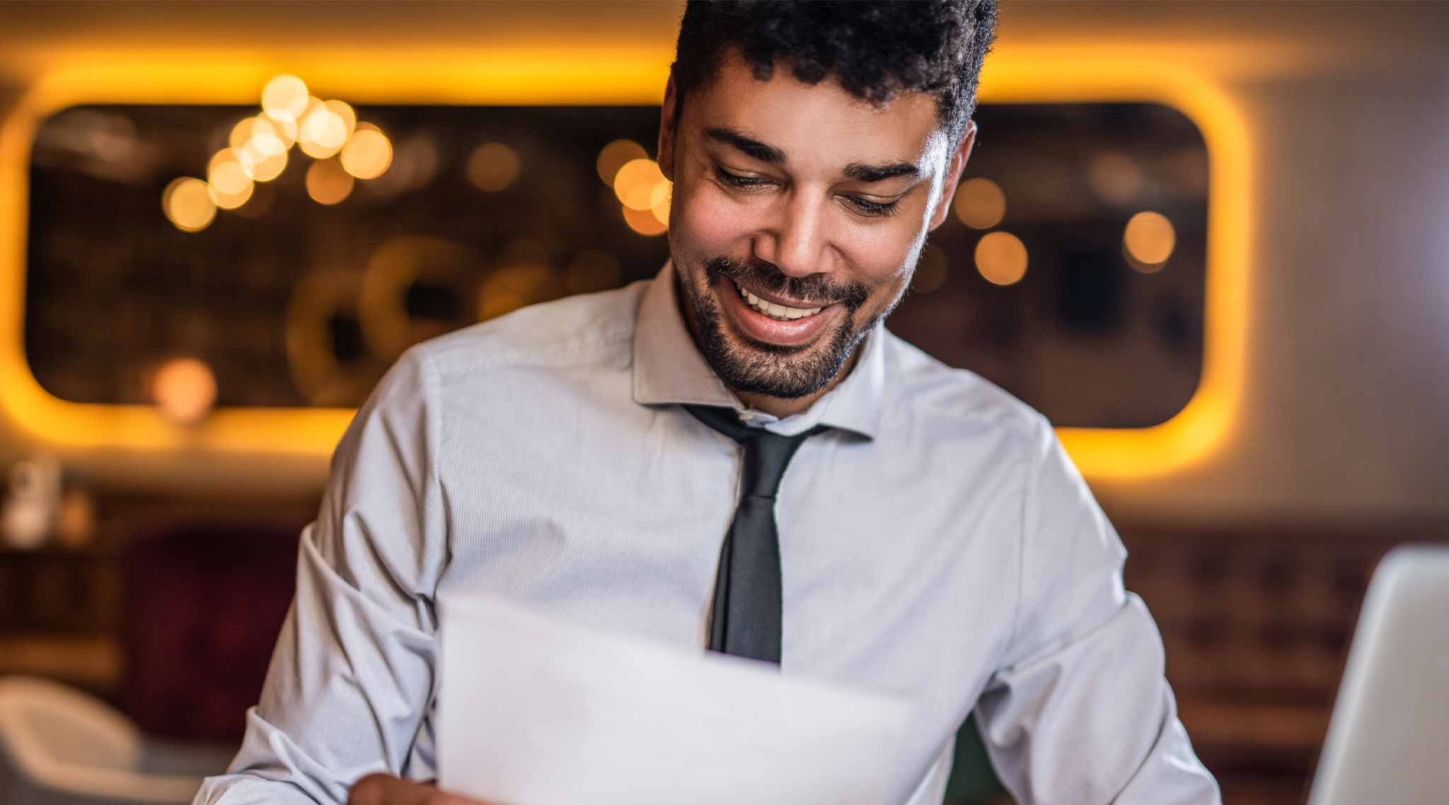 Man dressed in business casual looking at a paper.