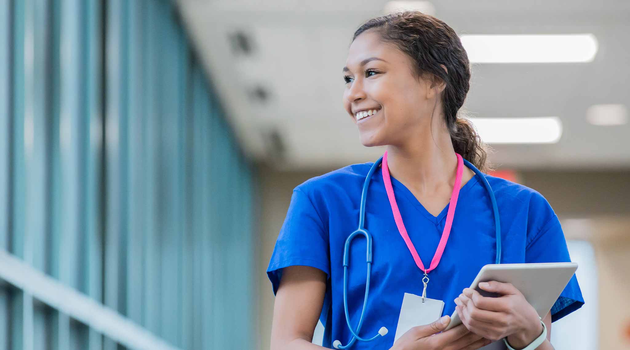 Nursing holding clipboard, looking off into distance and smiling.