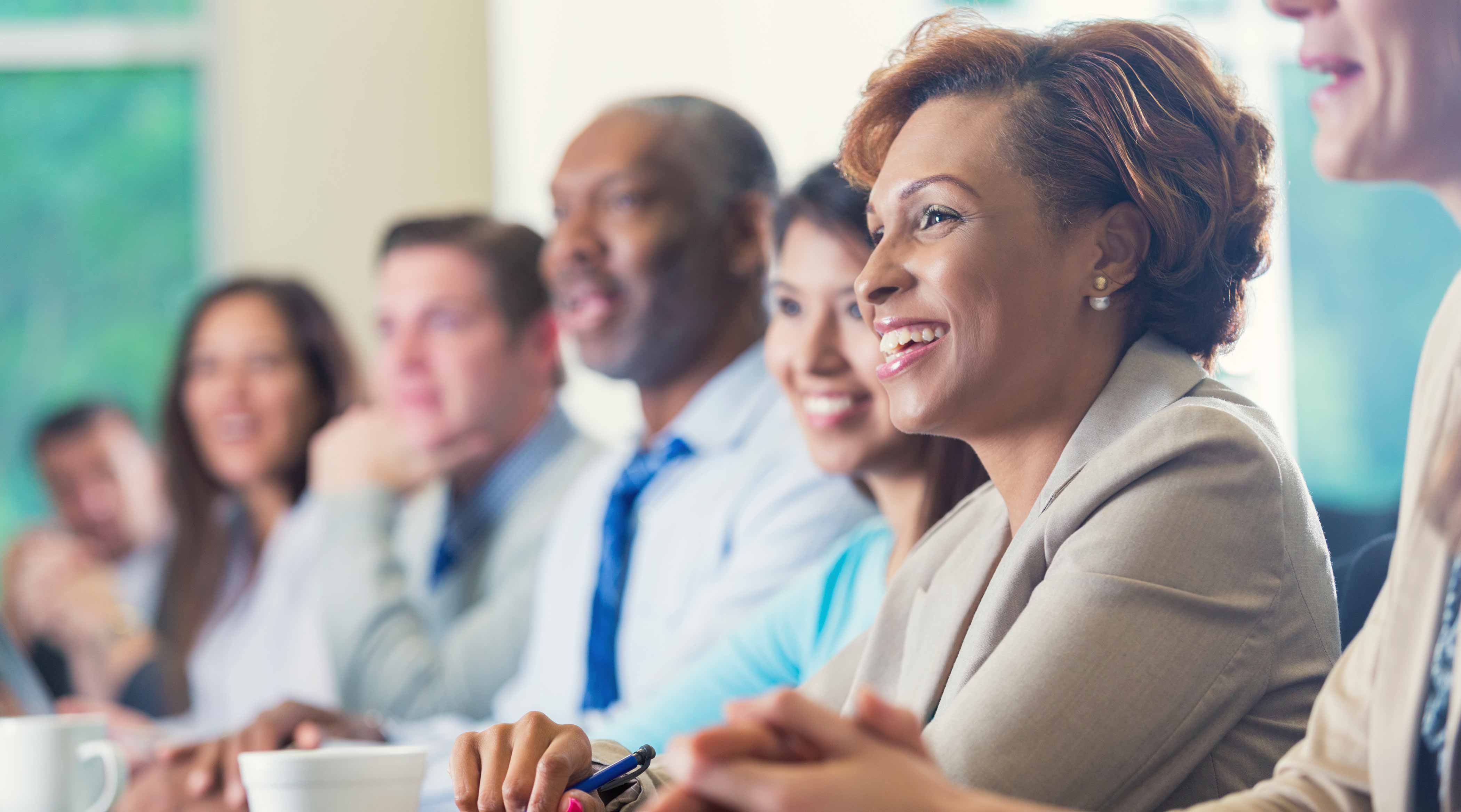 View of people sitting next to each other at a boardroom table.