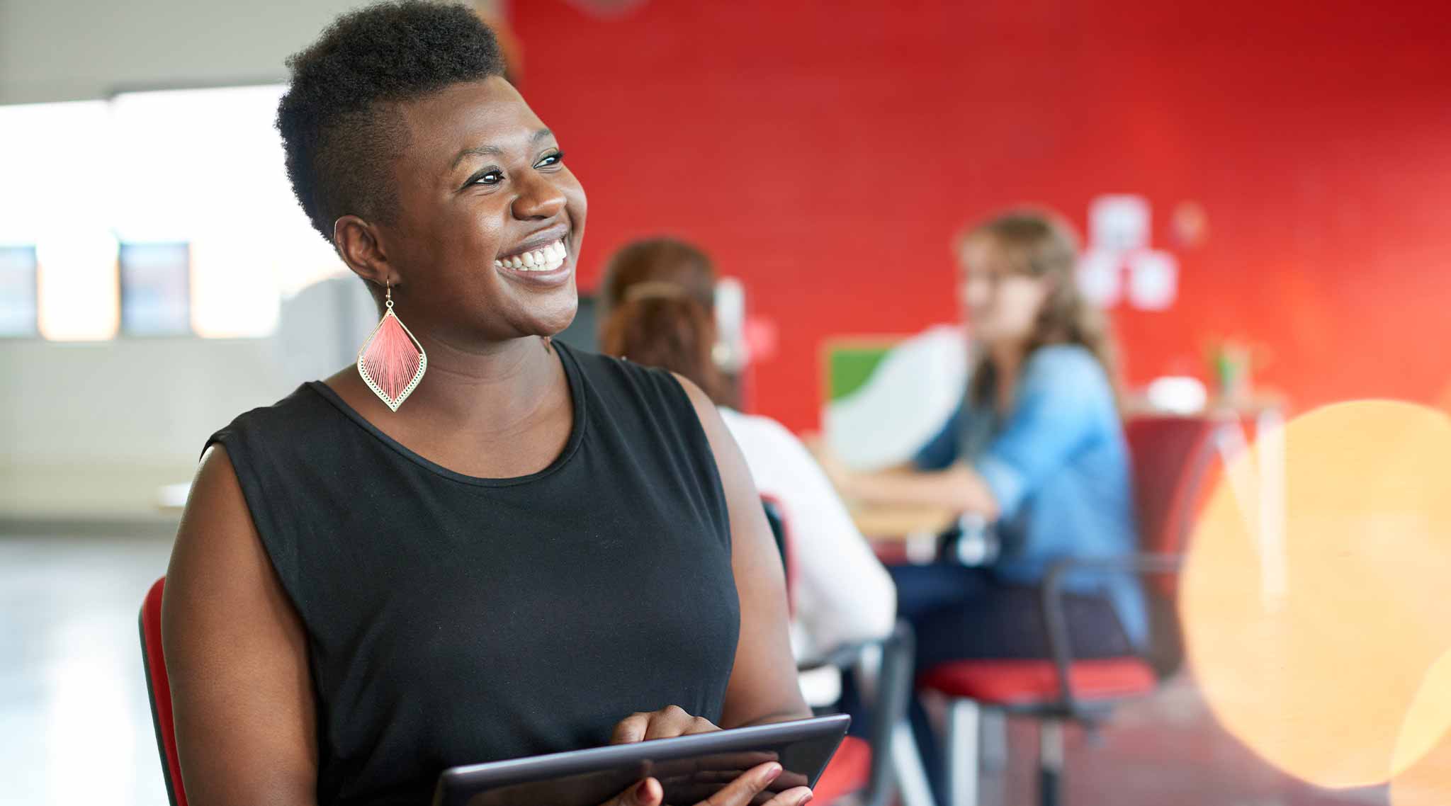 Women smiling and holding a tablet