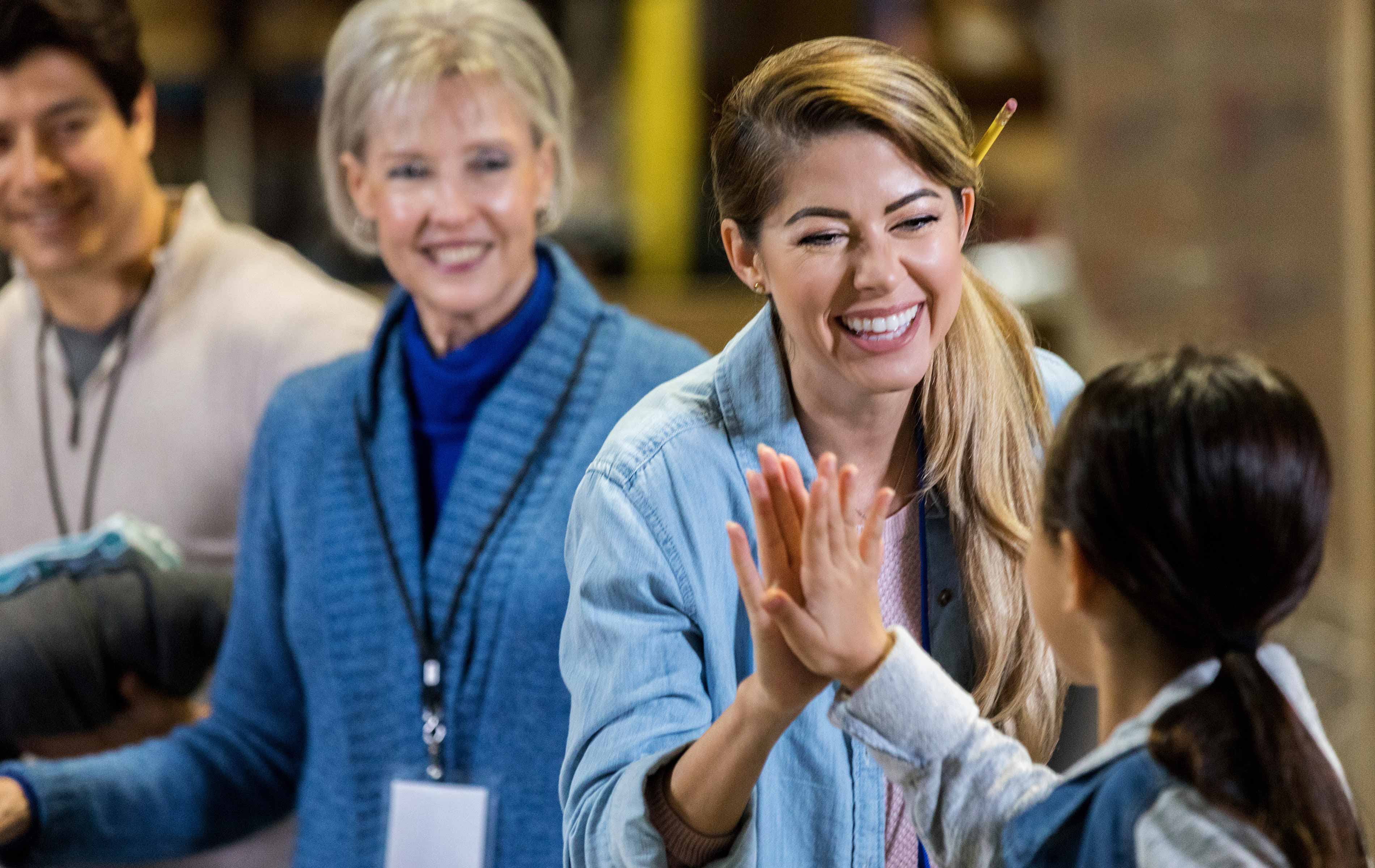 Social workers looking at a child, one woman giving the child a high five and smiling.