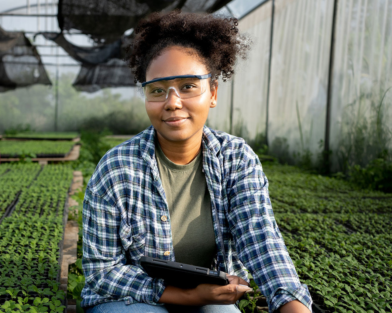 Woman standing in a greenhouse with a tablet
