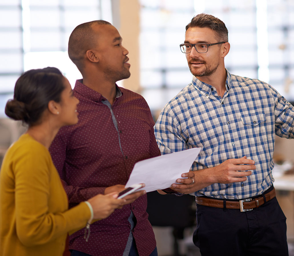 Three coworkers looking over a sheet of paper.