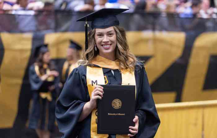Chelsea Hoyer, MSW, wearing her graduation cap and gown and holding her diploma at her commencement ceremony.