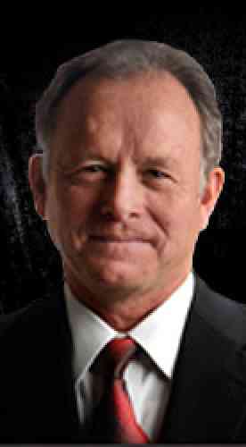 Photo of Steve Starr: Smiling caucasian man with dark gray hair wearing a suit and tie