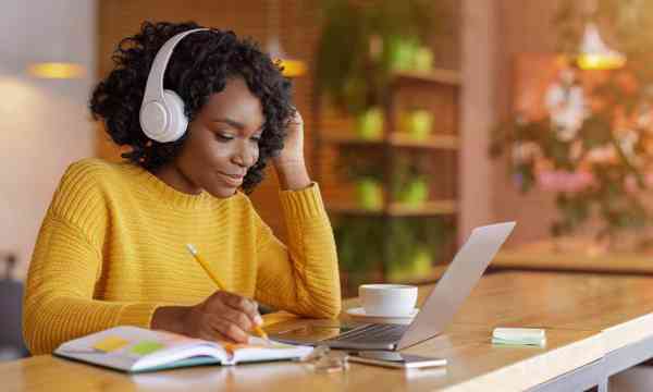 Smiling girl with headset studying online, using laptop stock photo.
