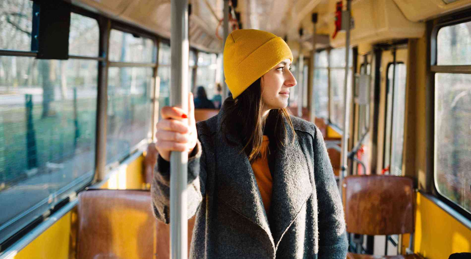 Young woman standing in a wagon of a driving tramway. Transportation, travel and lifestyle concept.