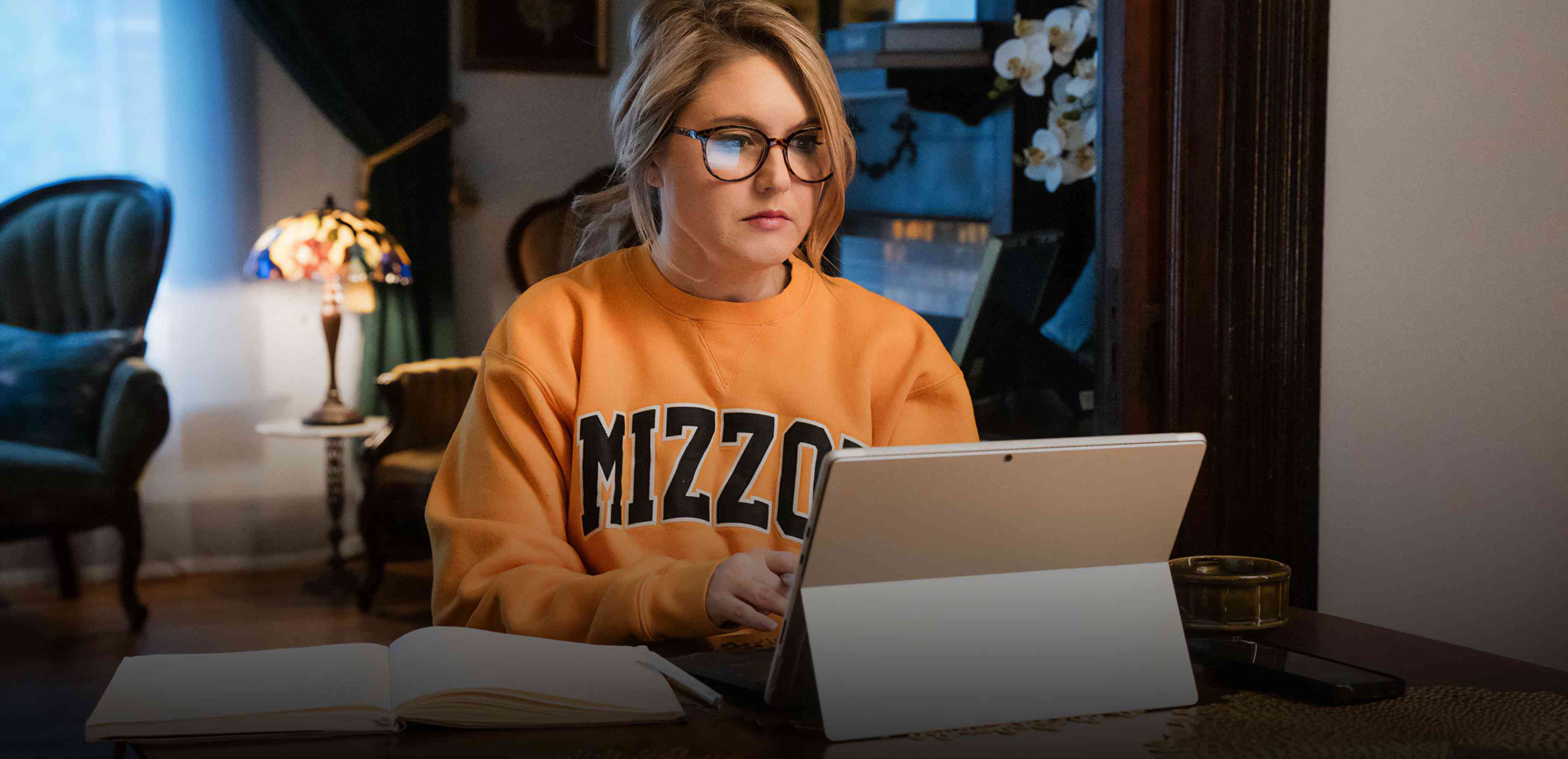 Blond woman studies on laptop at table wearing a Mizzou sweatshirt