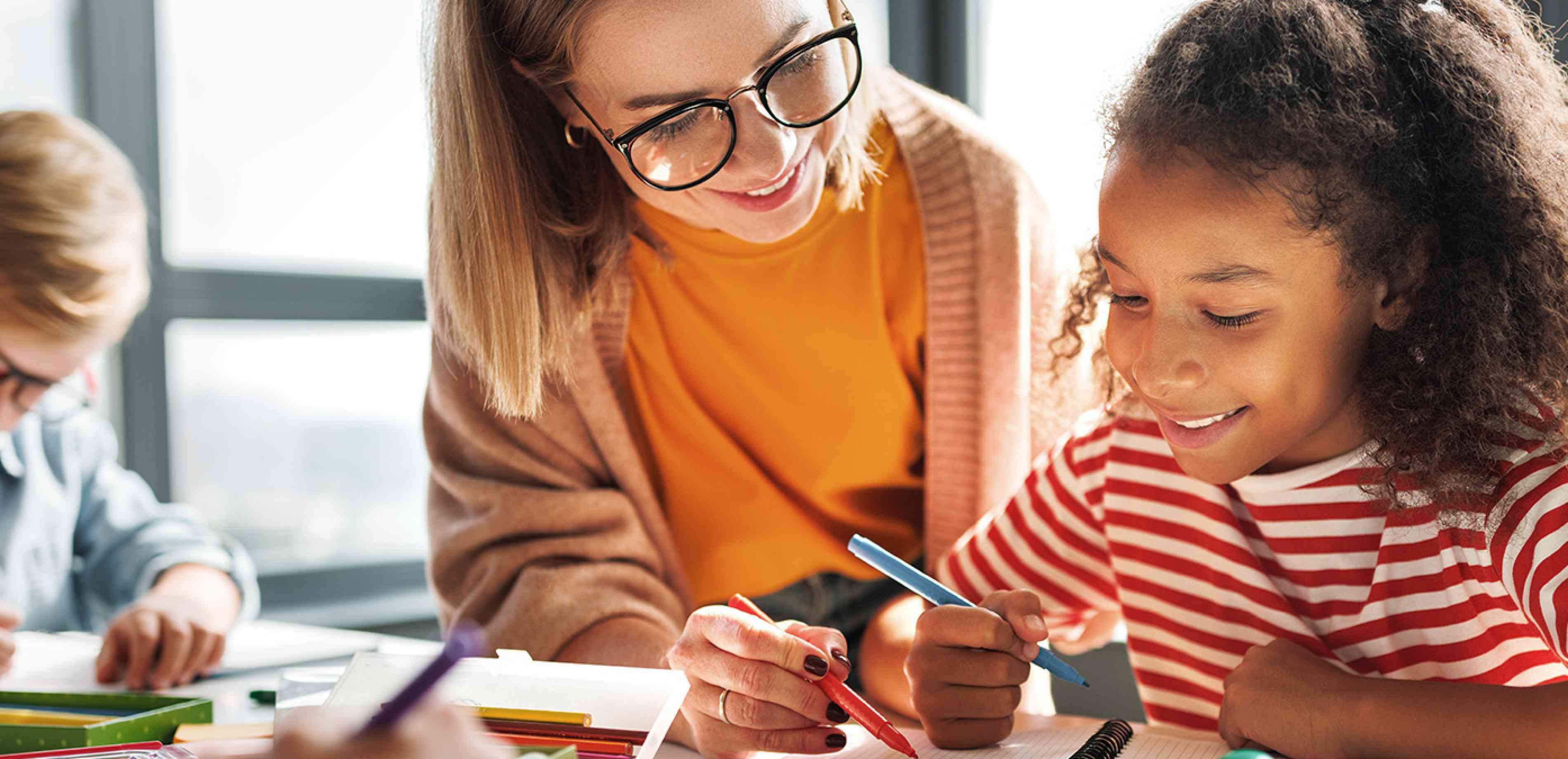 Teacher working in classroom with a student.