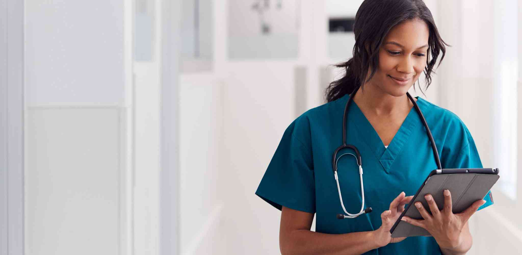 Nurse wearing scrubs looking at a tablet