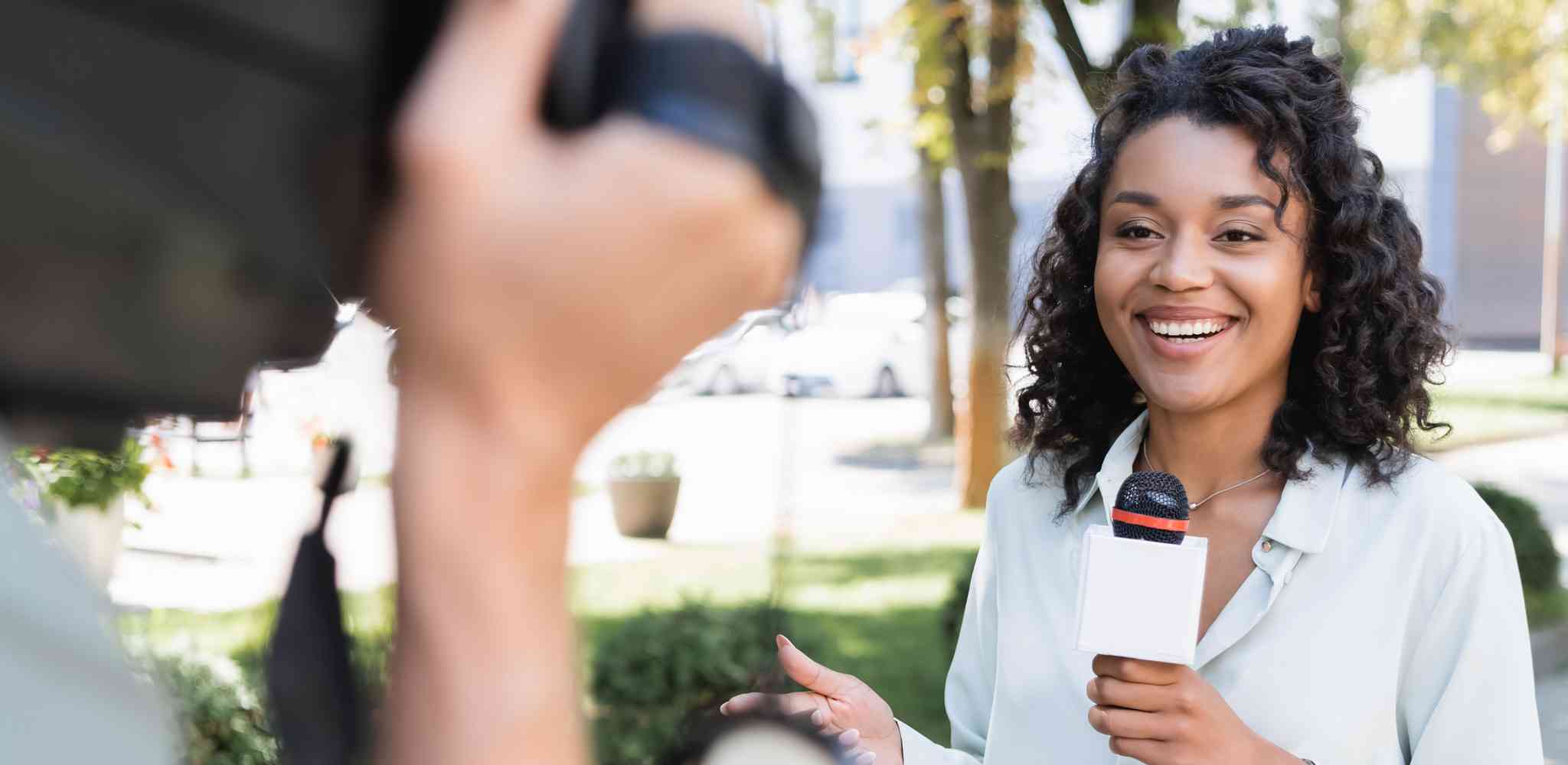 Reporter looking towards a camera while holding a microphone.