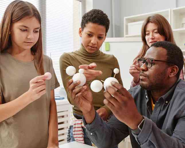 A teacher showing a molecular model to young learners.