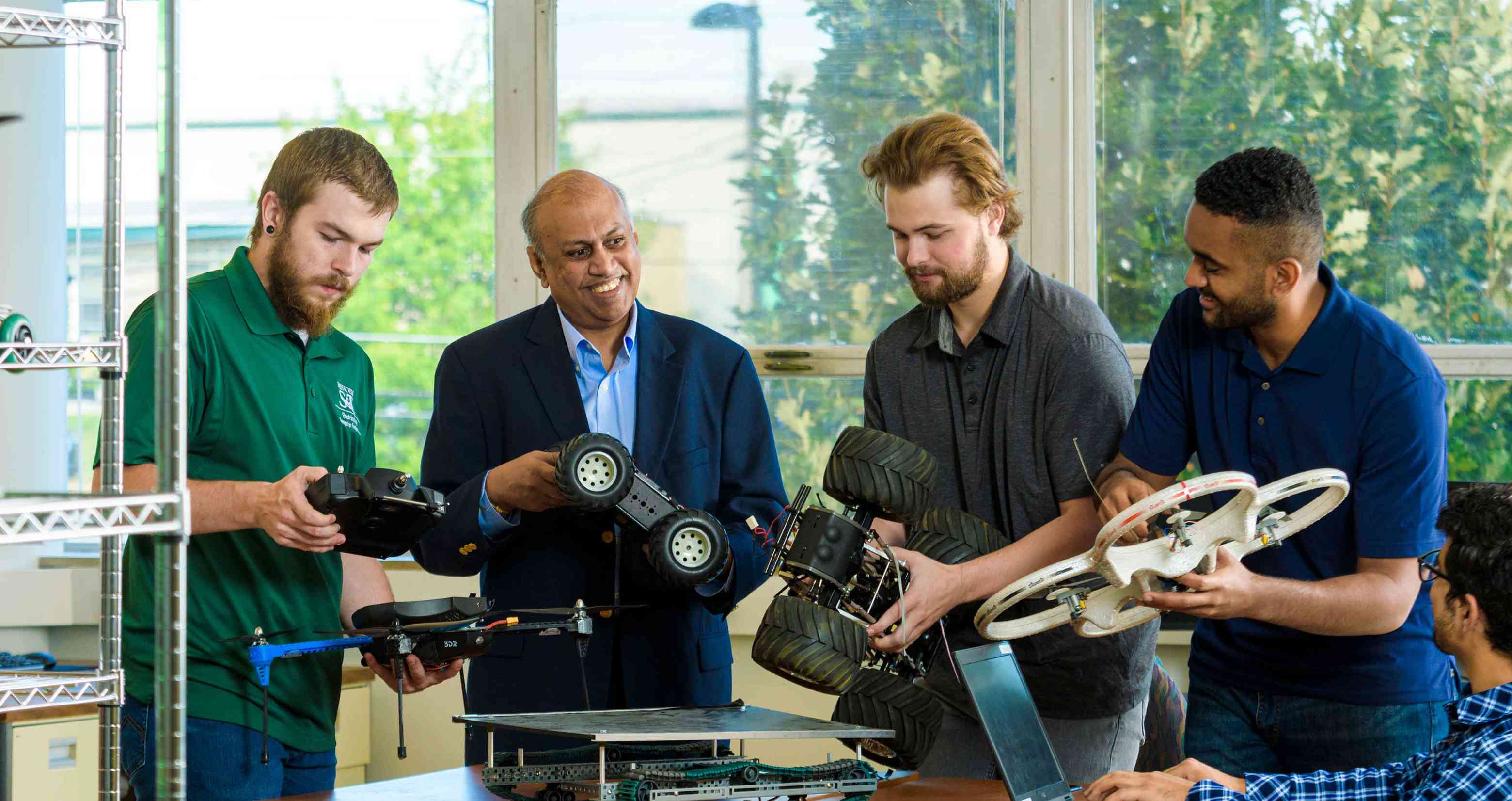 Professor showing a remote control vehicles to students.