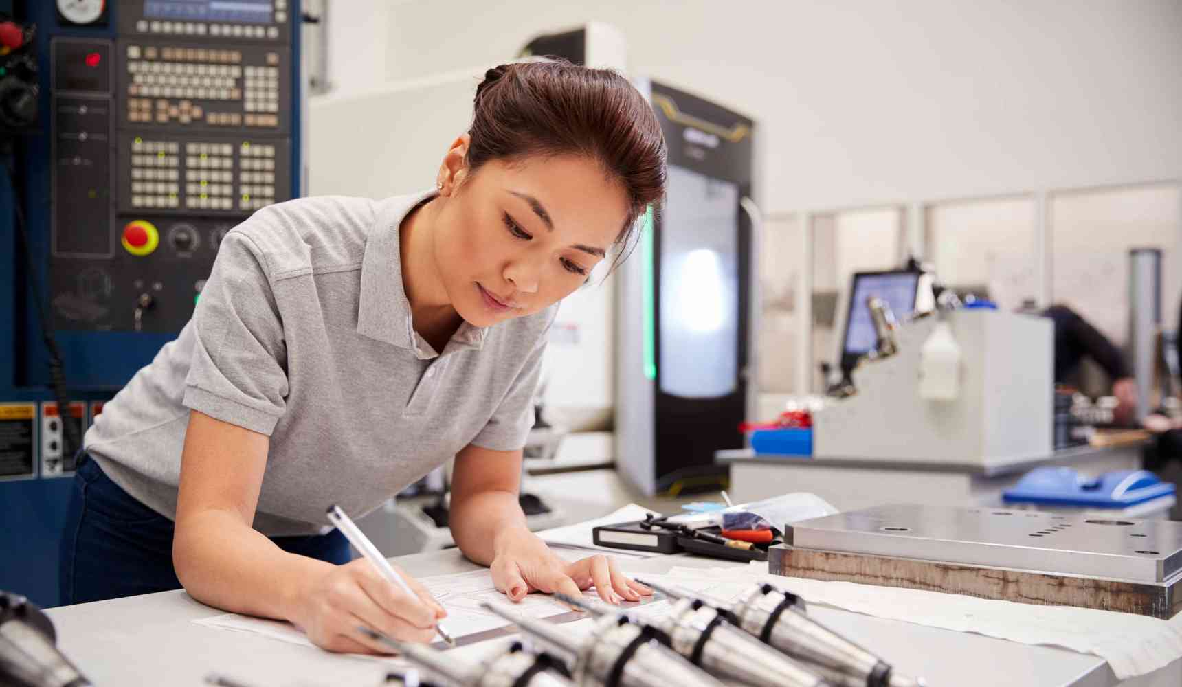 Female Engineer Measuring CAD Drawings In Factory