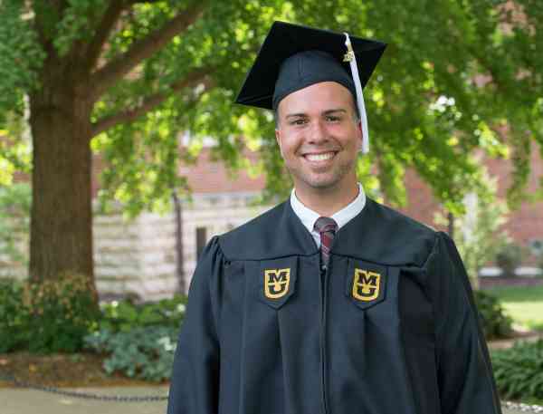 Nelson Perez, BGS, wearing his cap and gown on Mizzou's campus.