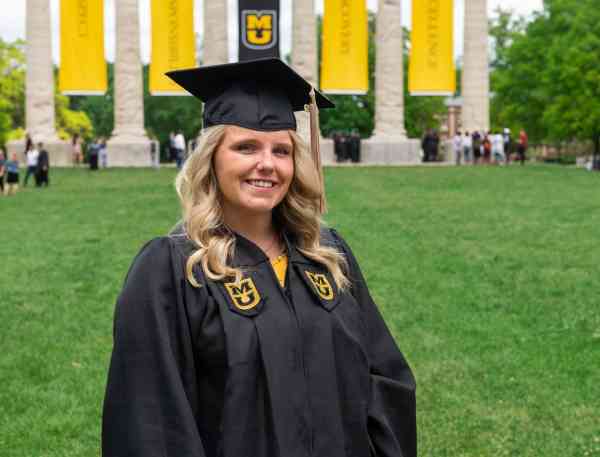 Sarah Swoboda, bachelor's in business administration ’19, wearing her graduation cap and gown, with the Mizzou columns behind her.