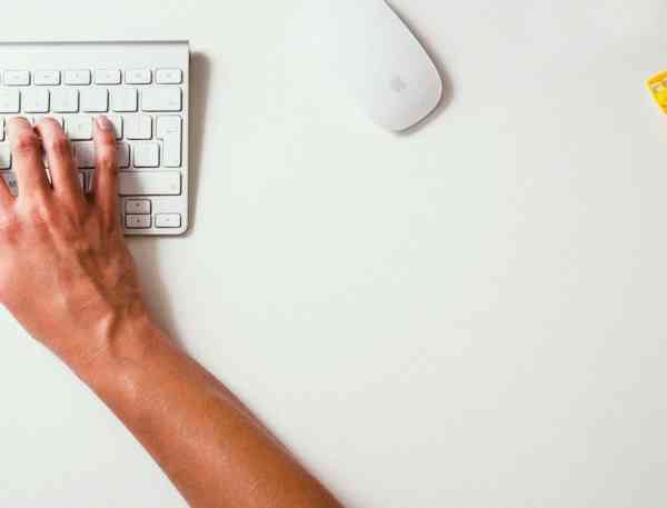 Overhead view of student typing on keyboard on desk.