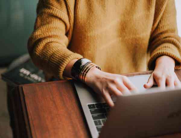 Student on laptop wearing a gold sweater.