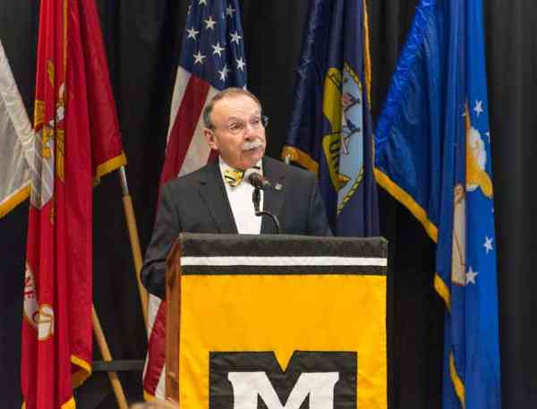 Chancellor R. Bowen Loftin standing at a podium and announcing new military tuition award to a crowd.