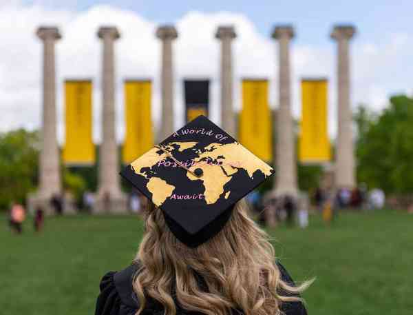 Sarah Swoboda, bachelor's in business administration ’19, faces the columns on Mizzou's campus at commencement; her graduation cap reads "A world of endless possibilities".