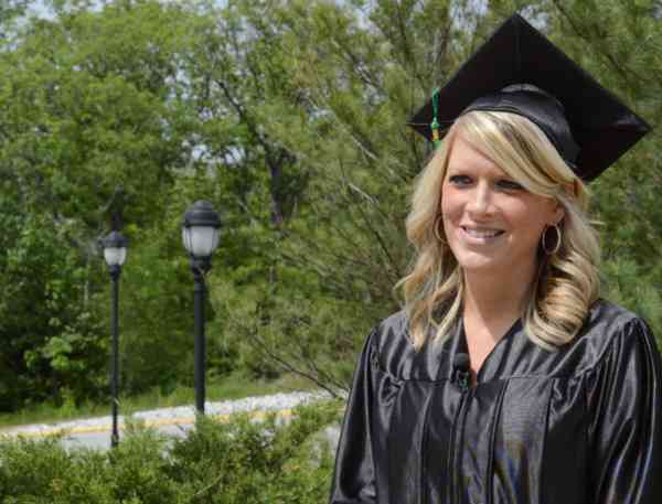 Graduate Alicia Reed on Mizzou's campus wearing graduation cap and gown.