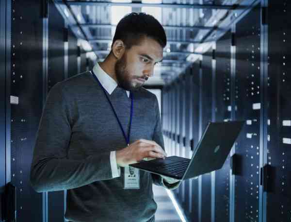 Working in a data center working on a laptop build holding it.
