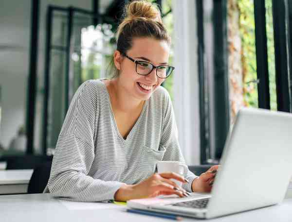 Women leaning into laptop computer at a desk.