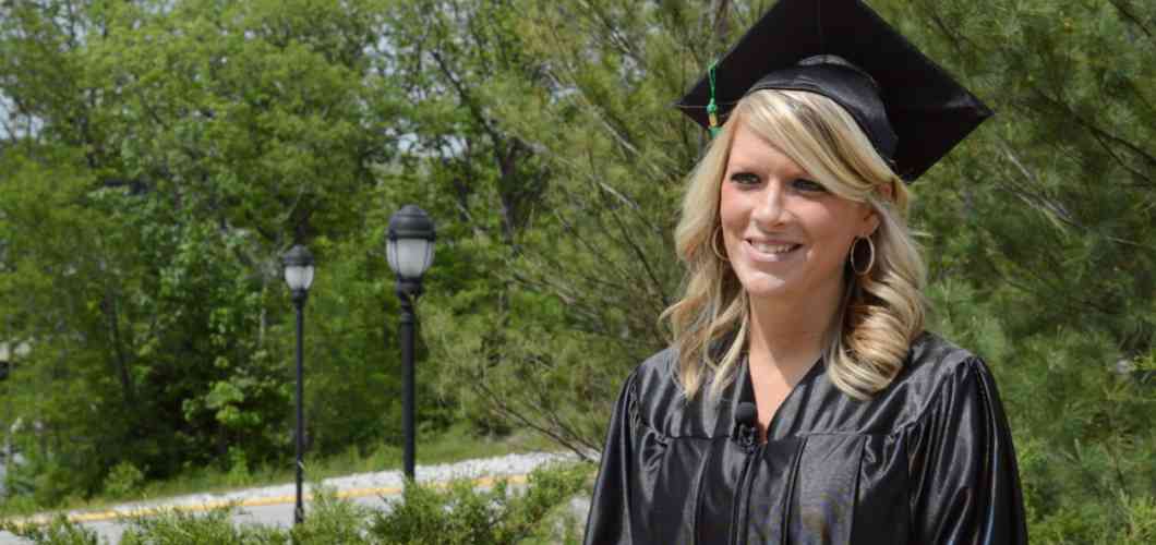 Graduate Alicia Reed on Mizzou's campus wearing graduation cap and gown.