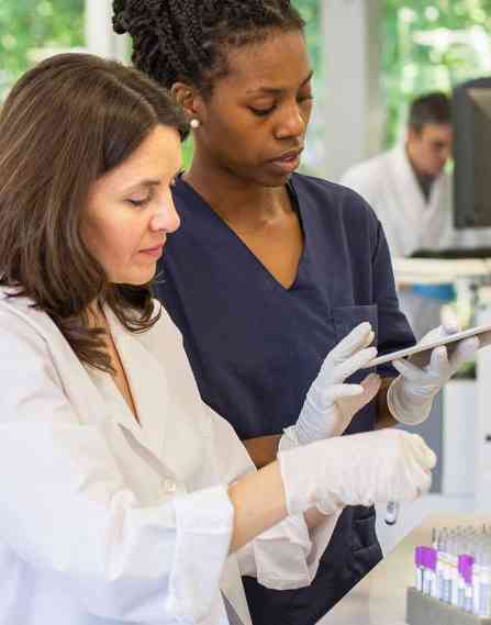 Two lab professionals working on a tablet next to some test tubes.