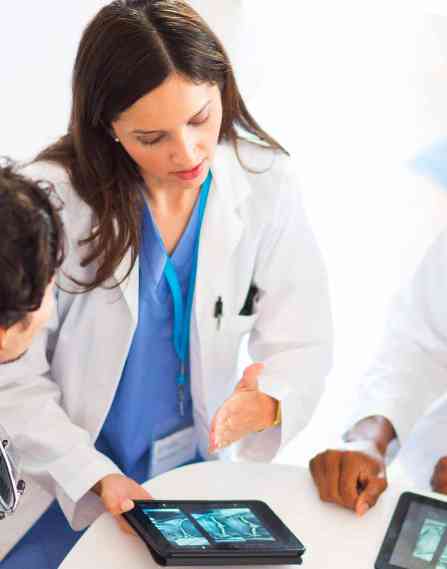 Three imaging professionals looking at x-rays on a tablet.