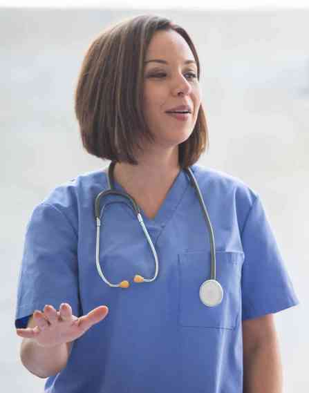 Medical professional wearing a stethoscope around their neck and speaking to two colleagues.