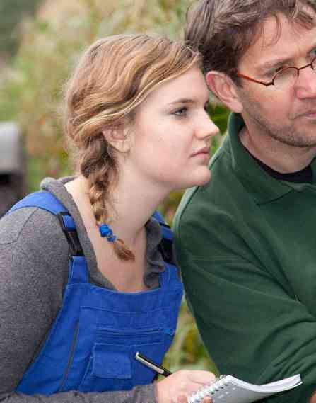 A student and professor working in a corn field.