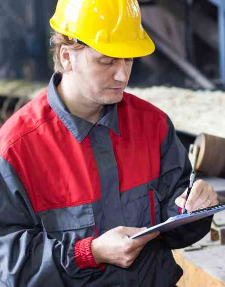 Food safety professional wearing a hard hat and holding a clipboard.