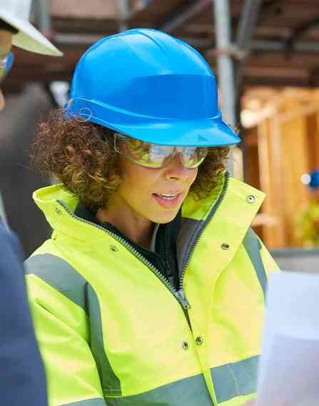 Civil engineer wearing a hard hat and talking to a colleague about a document.