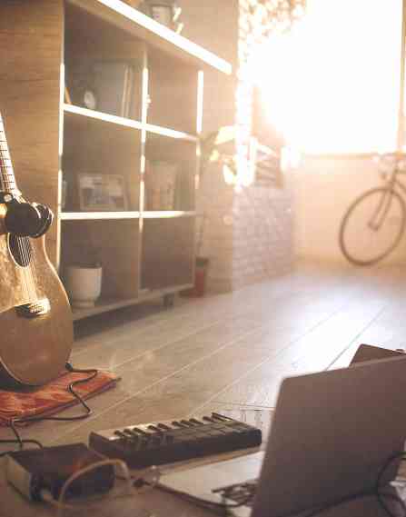 A room with a laptop and guitar.