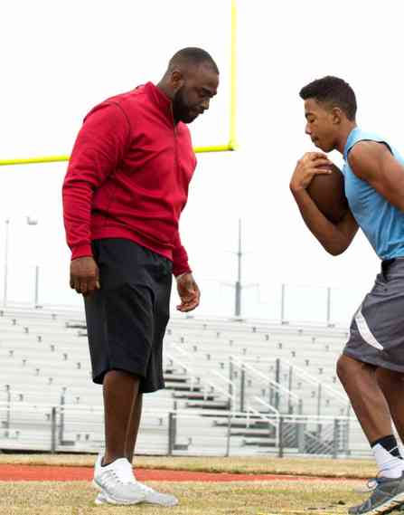 A black male coach works with a black male youth individually
