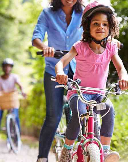 A child and parent riding bikes in a park.