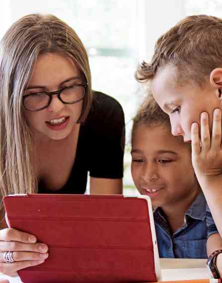 Teacher showing two students something on a tablet.