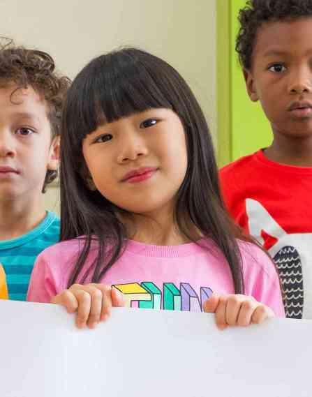 a small group of young multi-ethnic children holding up a large banner