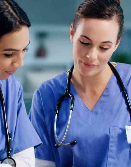 Two nurses looking down at a document.