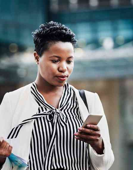 Professional carrying a clipboard and looking at a phone.