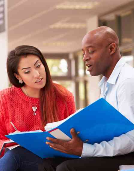 Two people reviewing documents from a binder in an office environment