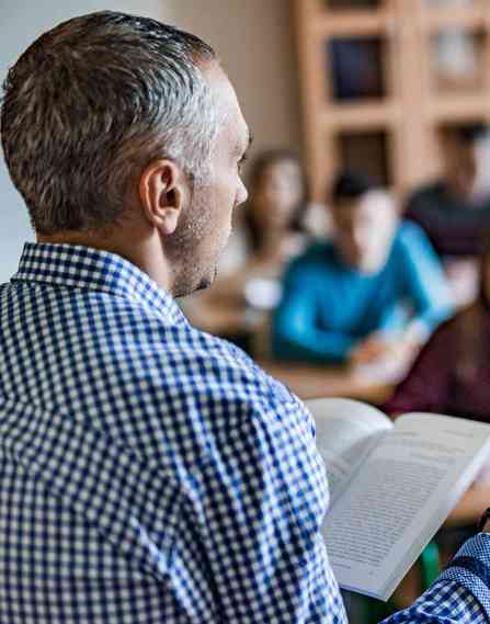 Teacher talking to group of students in a classroom.