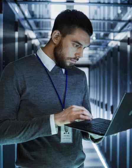 Working in a data center working on a laptop build holding it.