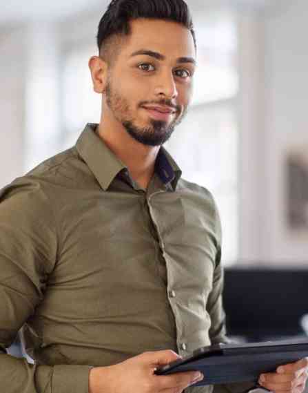 Person holding a tablet in a office environment looking at the camera smiling.