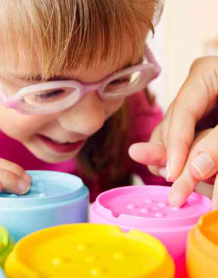 Hands of an occupational therapist helping a young child use some sensory toys.