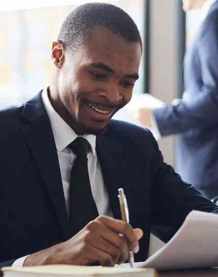 Person at a conference table holding a pen while looking at a group of papers.