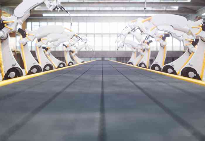 View from an assembly line conveyor belt lined with autonomous robot arms.